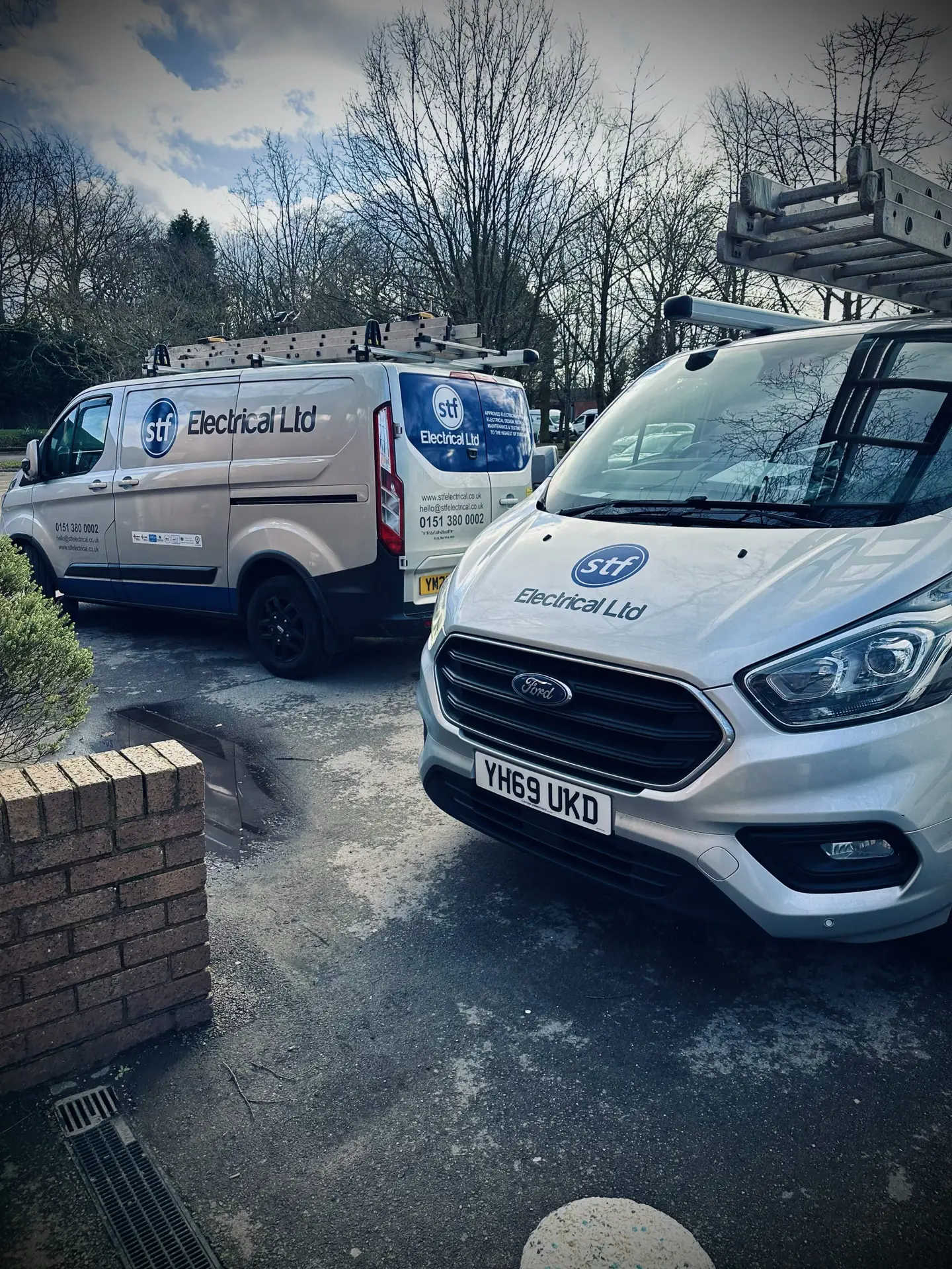 Two STF Electrical Ltd vans parked outside a high school undergoing a rewire project, showcasing our commitment to quality electrical services.